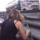 A woman takes a shit on the side of a busy highway.